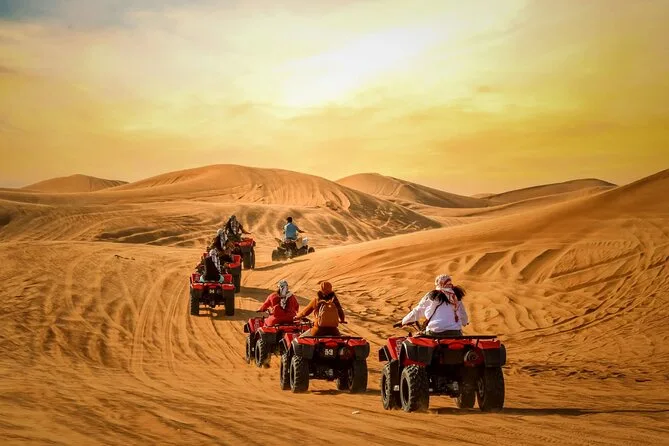 Quad bikes crossing golden dunes at sunset in the Al Wadi desert
