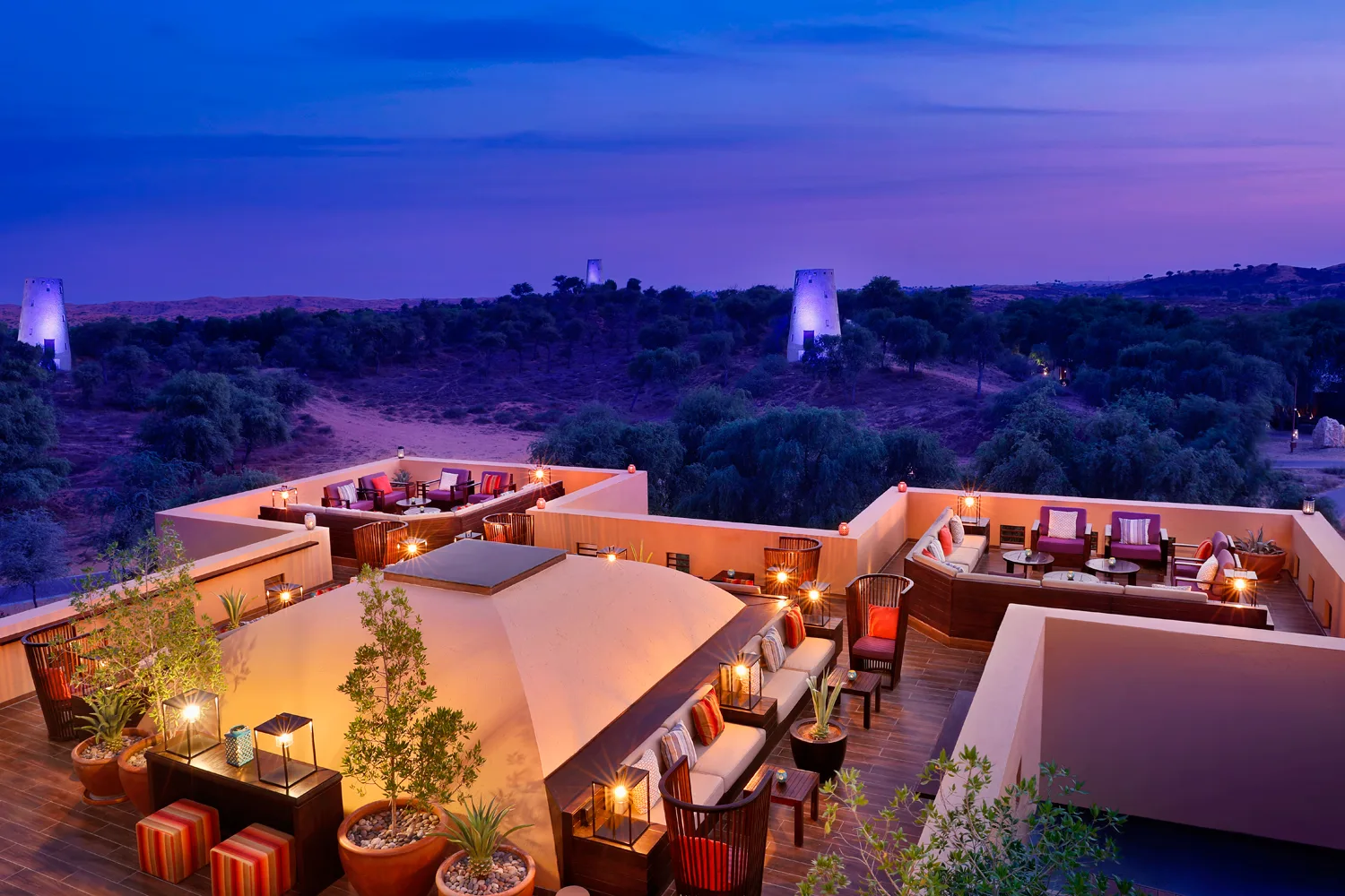 Lantern-lit desert resort terraces overlooking the Al Wadi Nature Reserve at dusk