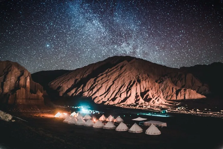 Desert camp tents glowing beneath a star-filled night sky