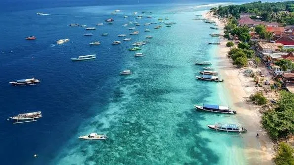 Boats anchored in clear water off a Gili Islands beach