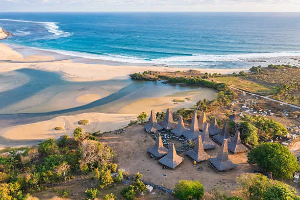 Aerial view of a traditional Sumbanese village with tall thatched roofs by the coast