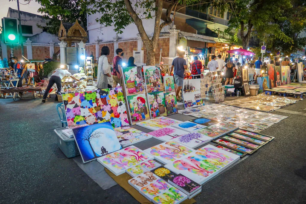 Paintings and handmade crafts laid out along the road at Chiang Mai Sunday Walking Street