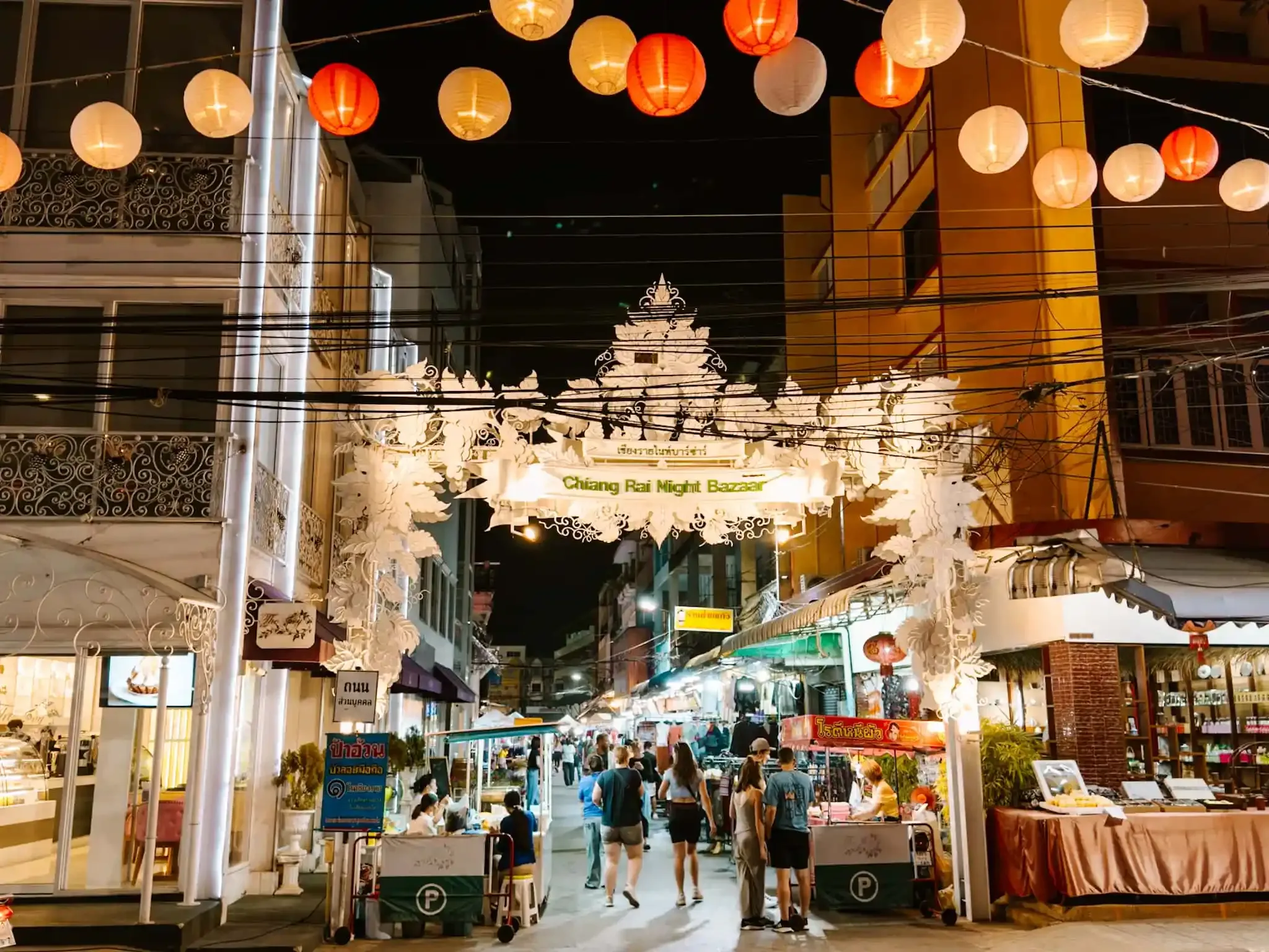 The ornate white entrance gate of Chiang Rai Night Bazaar strung with lanterns